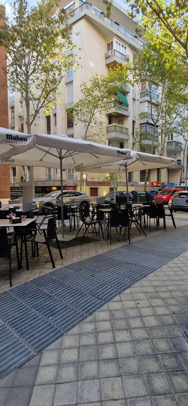 Terraza con mesas, sillas y sombrillas en la acera de la calle