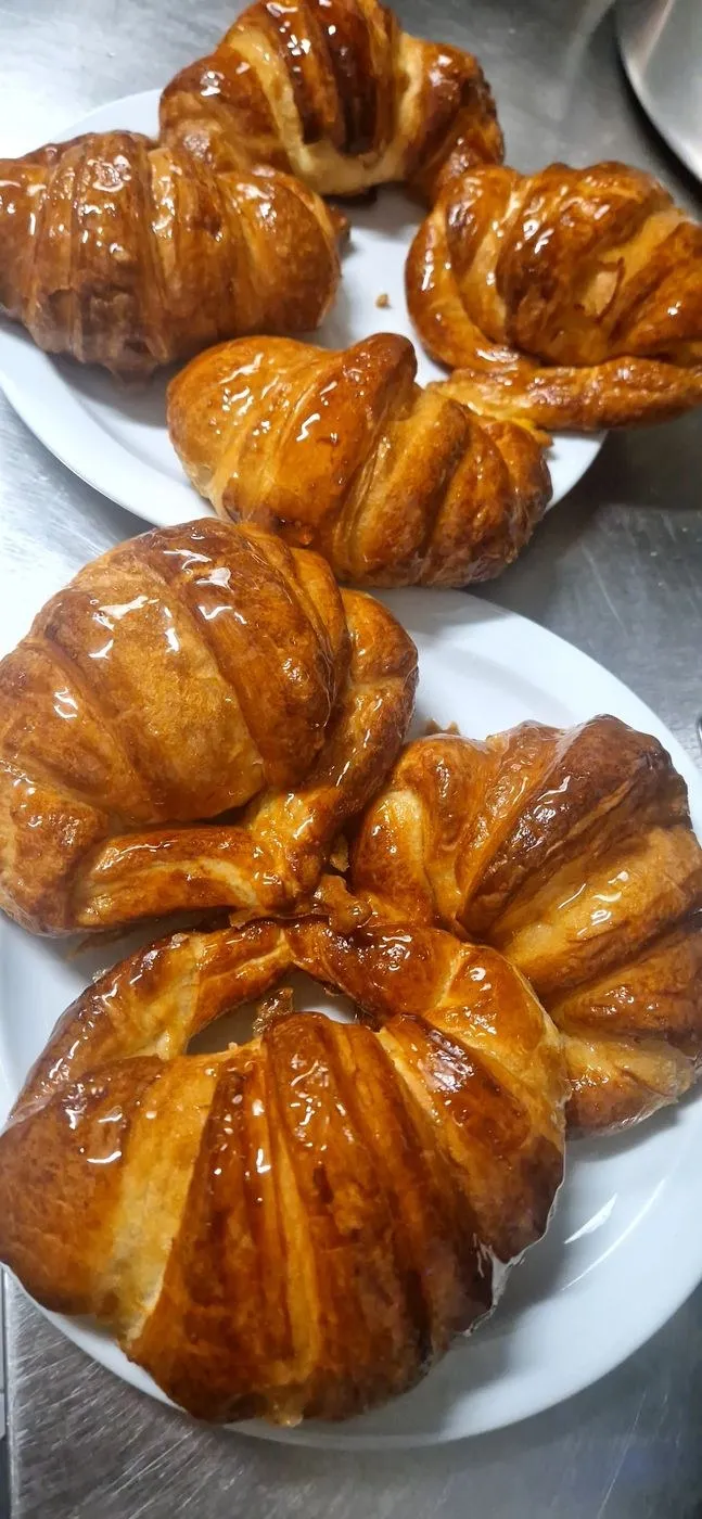 Seis croissants brillantes en platos blancos